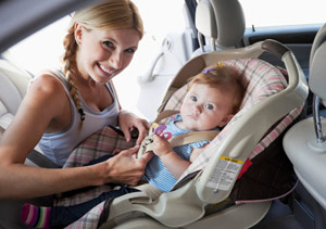mother putting baby in a car seat