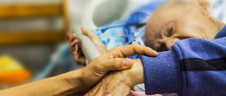 Bed-ridden elderly man receiving care.