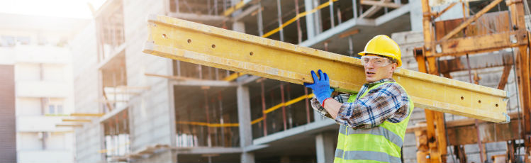 construction worker carrying steel beam