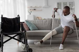 man getting up with crutches