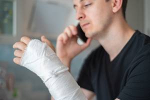 man with bandage on hand making phone call